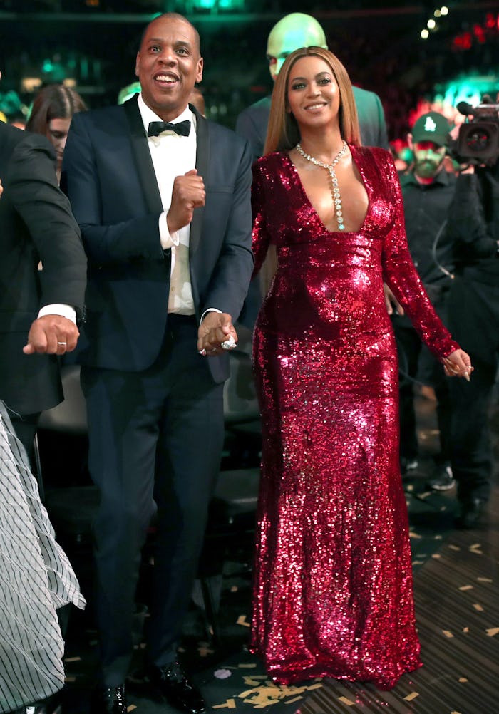 Beyoncé in a red sparkly dress walking with Jay Z in a suit
