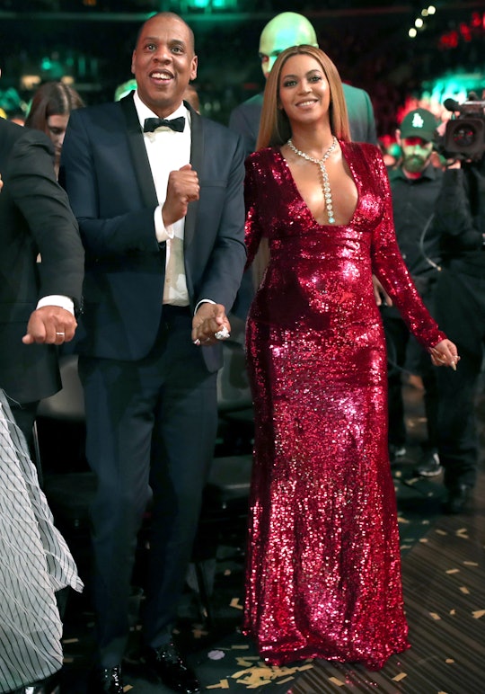 Beyoncé in a red sparkly dress walking with Jay Z in a suit 