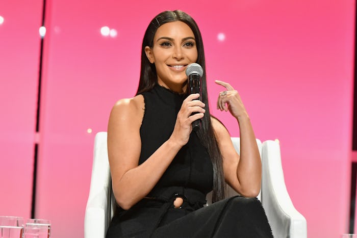 Kim Kardashian in all black with her hair down talking into a mic about using a surrogate