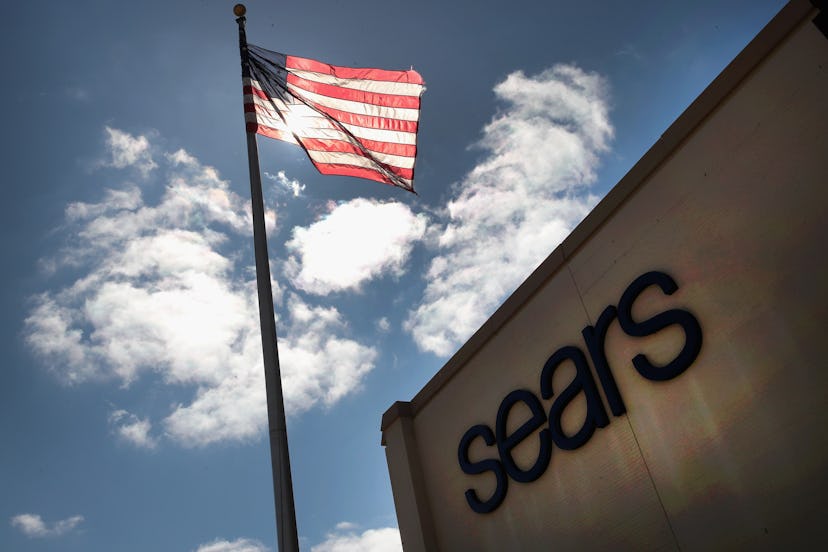 Sears brand sign on a building next to the American flag.