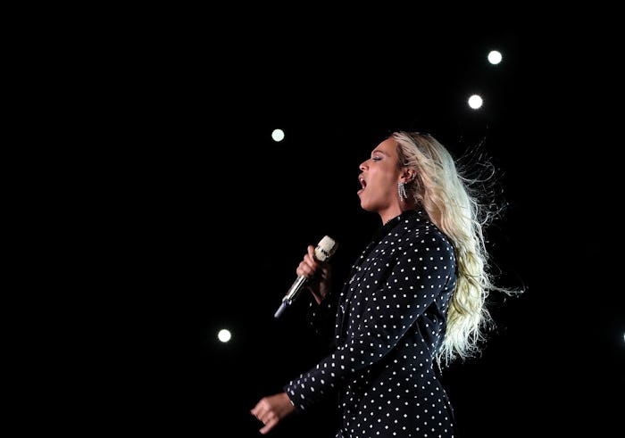 Beyoncé performing on stage in a black polka-dot dress 