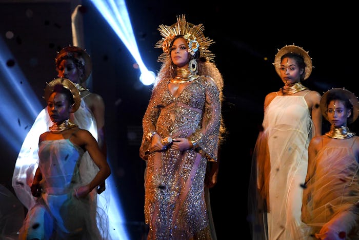 Beyoncé performing pregnant in a golden dress with a golden crown and backup dancers 