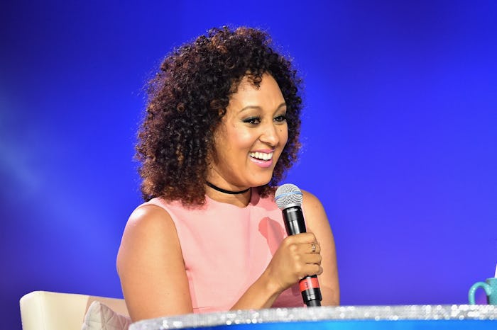 Tamera Mawry in a light pink sleeveless dress, talking into a microphone