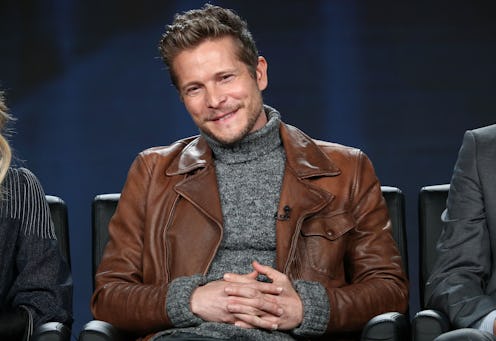 'The Resident' Star, Matt Czuchry, wearing a grey rollneck and a brown leather jacket.