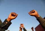 A Black woman holds two fists up. These quotes from Black leaders can be excellent Black History Mon...
