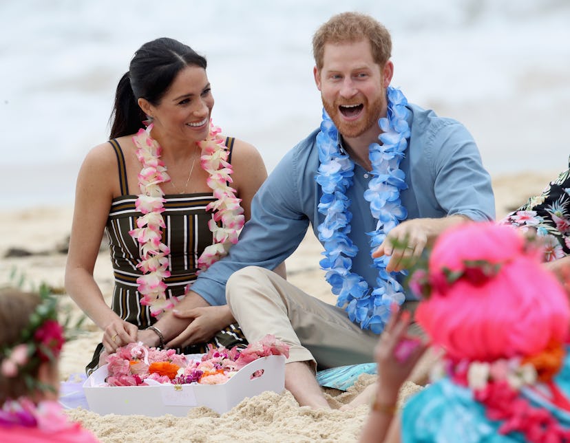 Meghan and Harry sitting at a sand beach 