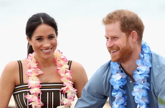 Prince Harry and Meghan Markle smiling with flowers around their necks