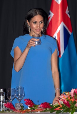 Meghan Markle standing and holding a glass