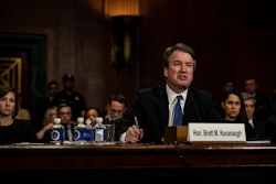 Brett M. Kavanaugh sitting at a table and giving a speech