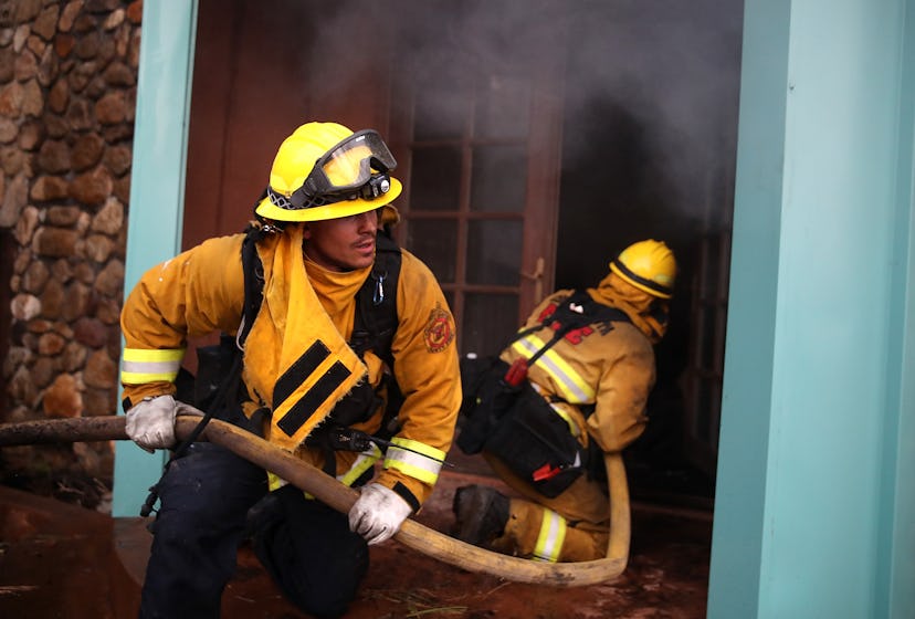 Firefighters taking a hose in the burning house during California wildfires