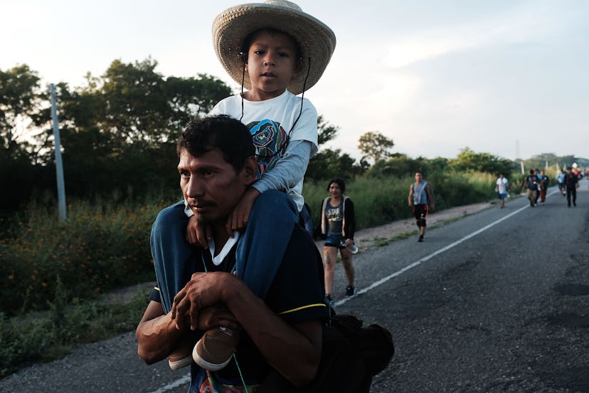 A migrant man carrying his son on his shoulders