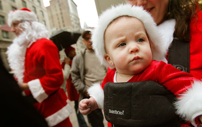 a baby wearing a santa suit in a baby bjorn