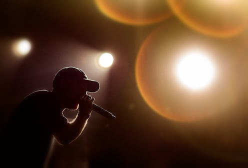 A singer with a cap under the stage lights during his performance
