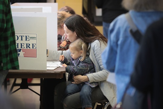 A mother voting with her kid in her lap.