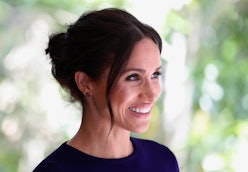 Meghan Markle with an updo and a minimalist makeup smiling for a photo