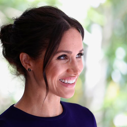 Meghan Markle with an updo and a minimalist makeup smiling for a photo