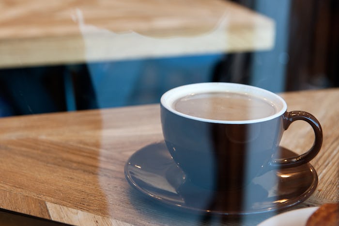 A cup of coffee in a brown cup on a wooden surface, that can help with a pesky skin condition