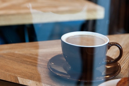 A cup of coffee in a brown cup on a wooden surface, that can help with a pesky skin condition