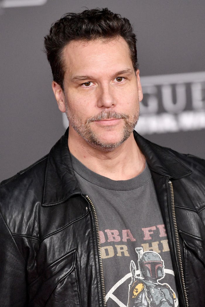 Dane Cook in a black leather jacket and grey t-shirt on a red carpet