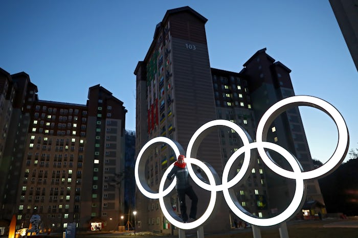 Tall buildings in a city with the 2018 Winter Olympics neon logo glowing