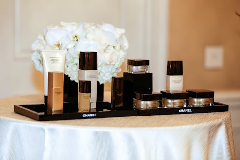 Chanel Beauty products displayed on a table with a white cloth and a bouquet of white roses.