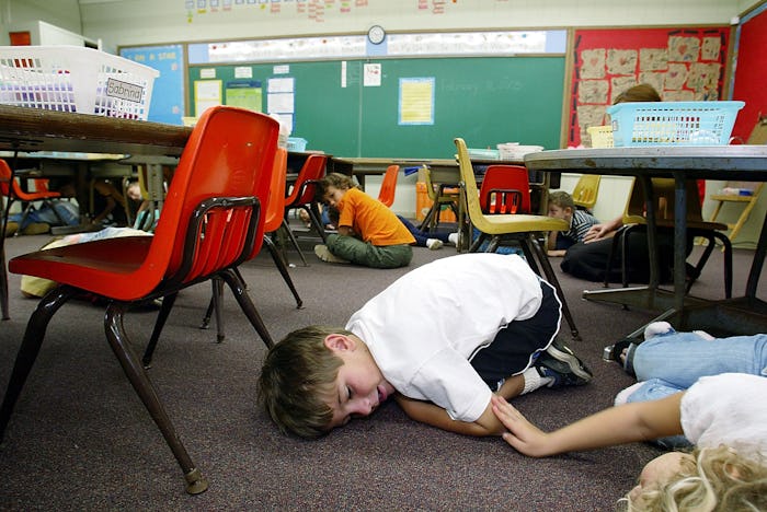 A boy and a girl lying on the floor in school because of an active-shooters situation