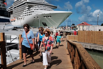 Tourists leave the cruise ship as they walk away on the small wooden bridge.