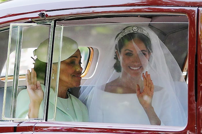 Meghan Markle on her wedding day, sitting in a car with her mother while they're waving