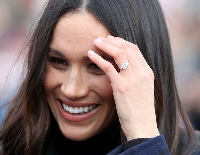 Meghan Markle smiling, while moving her hair away with her hand with the perfect manicure