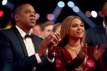 Jay-Z, in a black tuxedo and white shirt, and Beyonce, in a red sequin dress applauding at the Gramm...