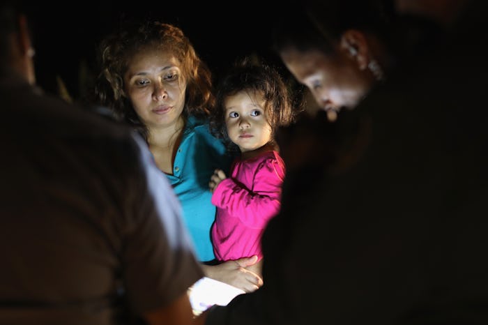 Immigrant mother standing in dark and holding her kid