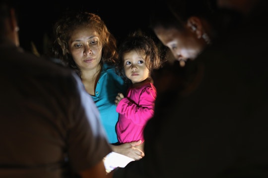 Immigrant mother standing in dark and holding her kid