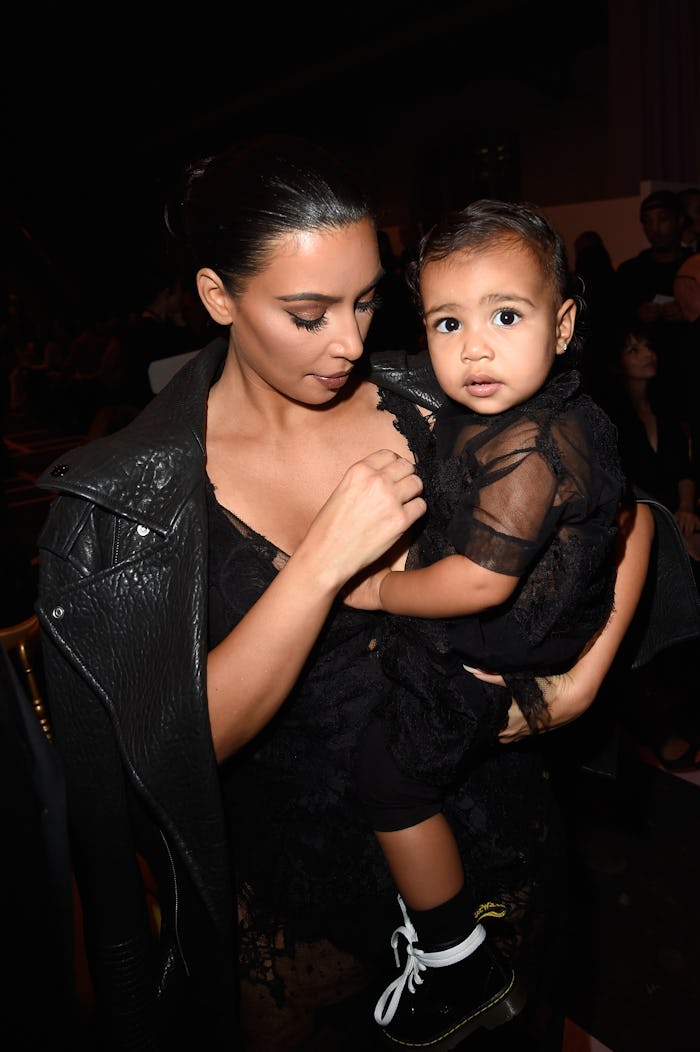 Kim Kardashian holding North as they are wearing matching dresses