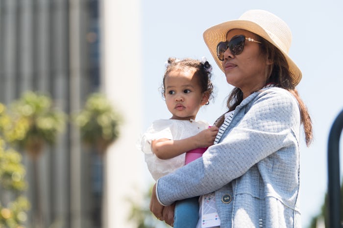 Chrissy Teigen holding her child at the Families Belong Together protest