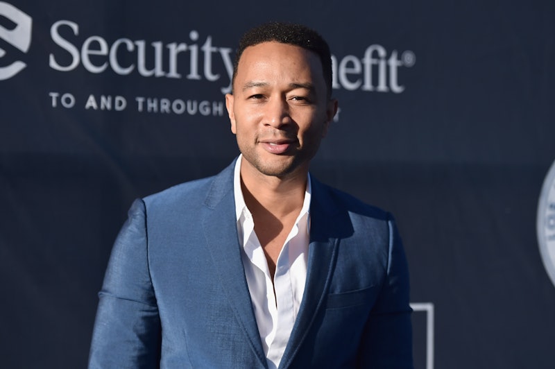 John Legend, wearing a blue blazer over a white shirt while posing for a photo