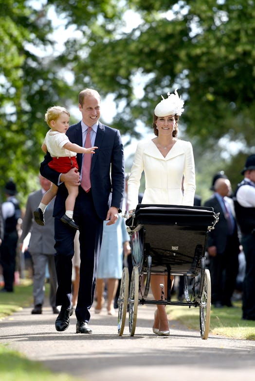 Prince William and Kate Middleton walking with Prince George and Princess Charlotte in a baby stroll...