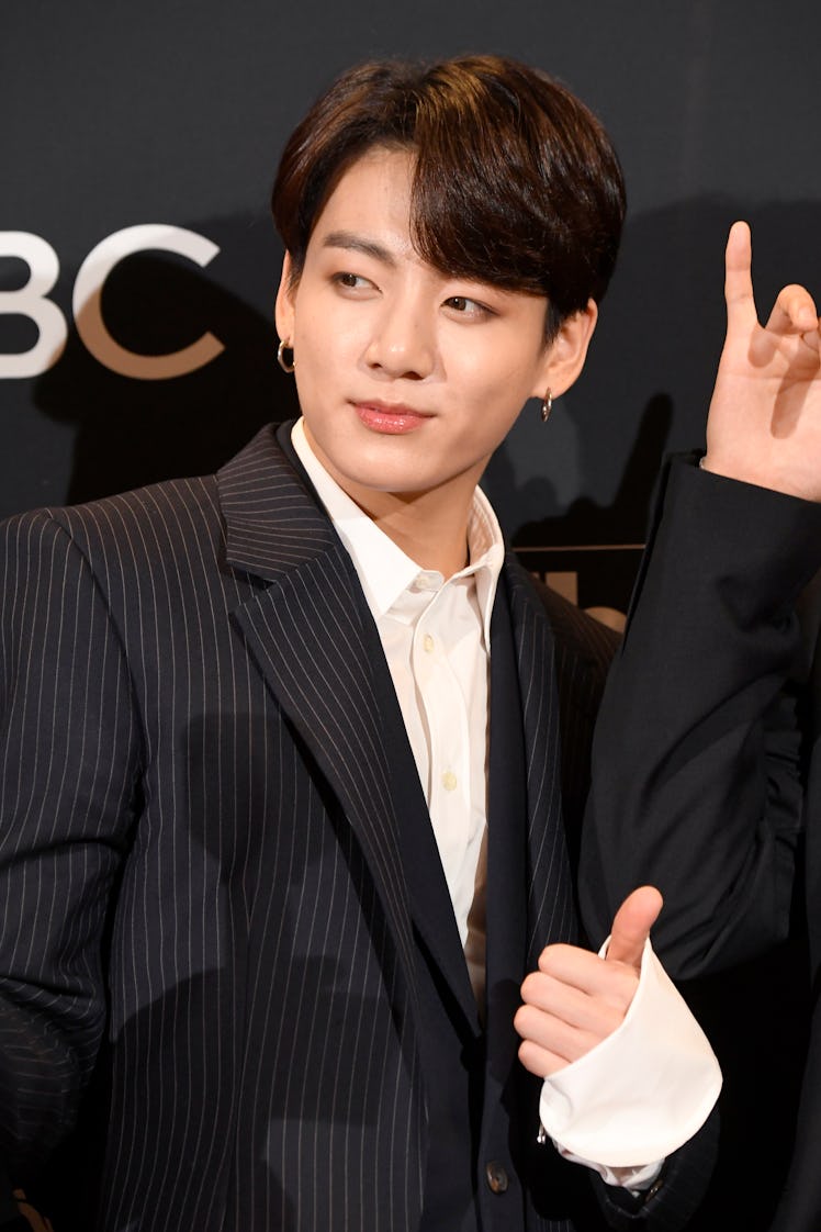 Jungkook from BTS rocking a shorter hairstyle while posing on a red carpet.