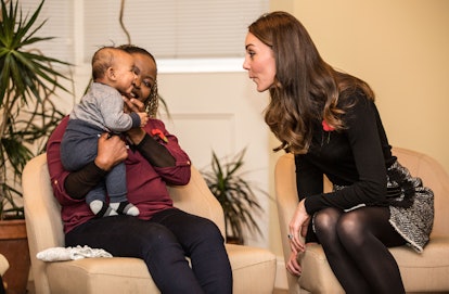 Kate Middleton makes a silly face at a baby.