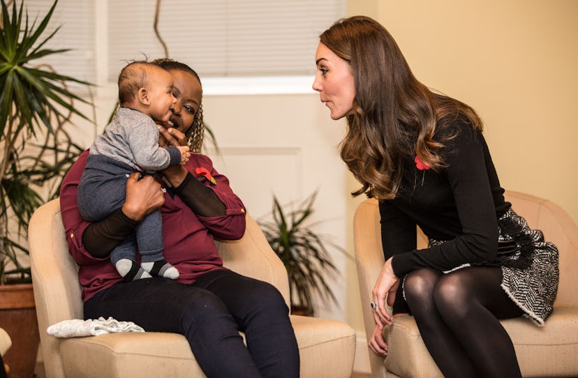 Kate Middleton makes a silly face at a baby.