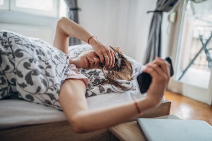 A woman checks her phone right after waking up