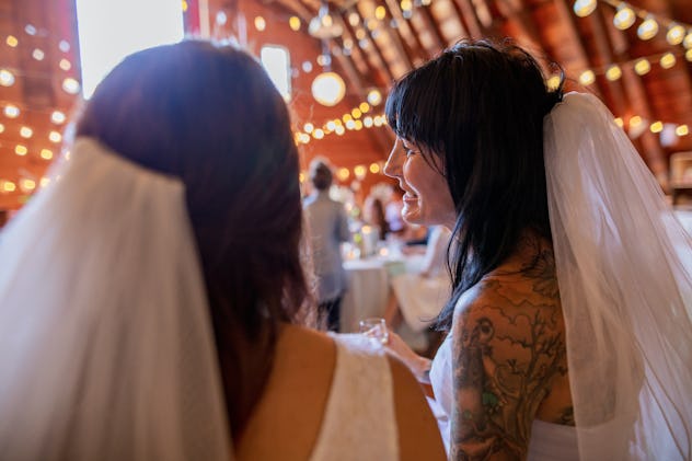 Two brides seated at wedding wearing matching veils