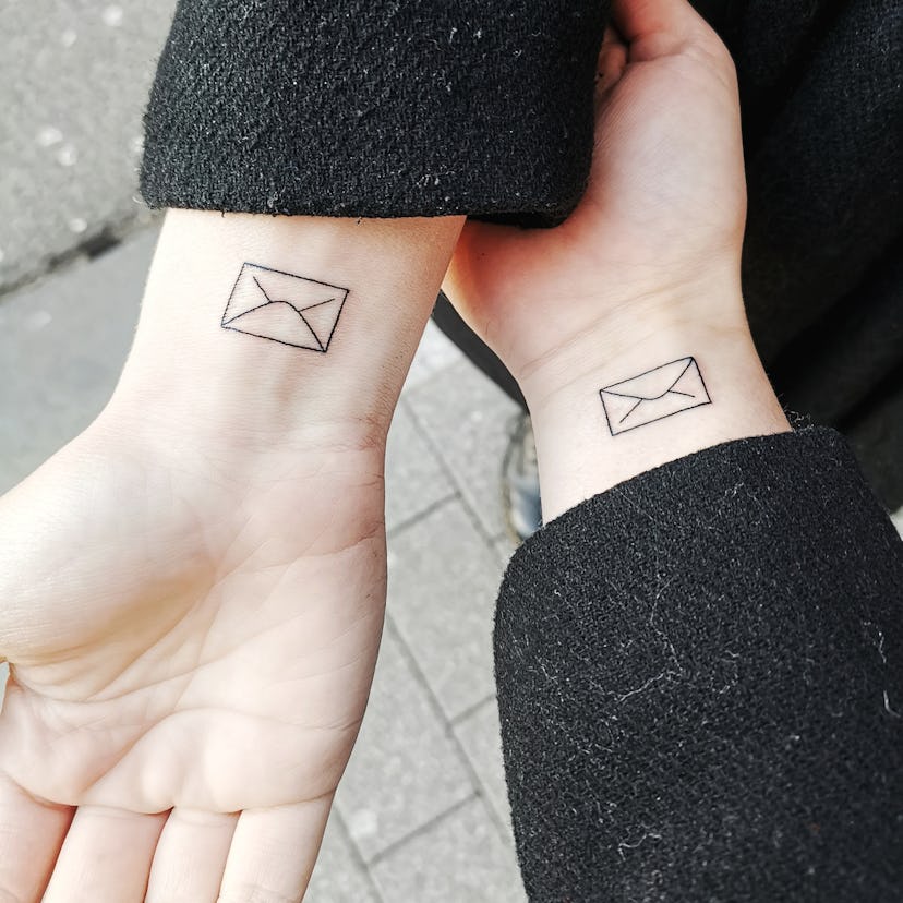 matching envelope tattoos on two wrists 