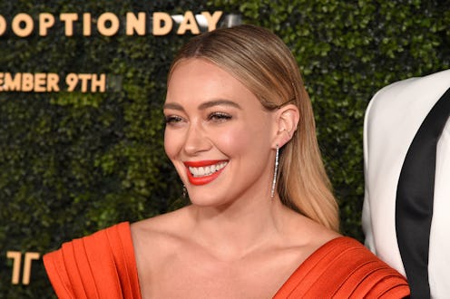 Hilary Duff poses in a burnt orange-colored dress.
