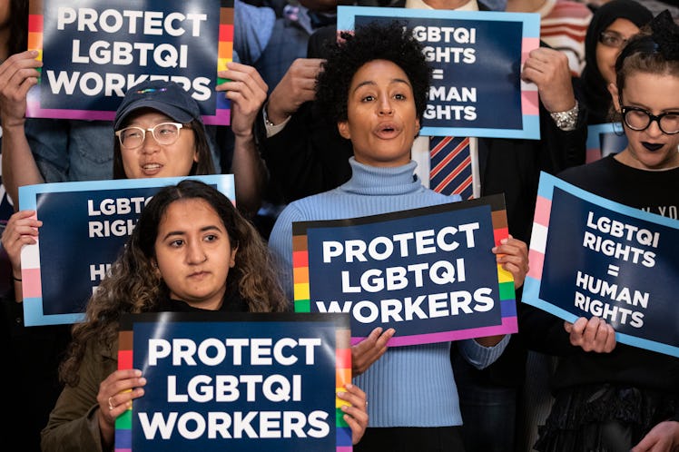 People holding LGBTQ rights signs ahead of Supreme Court hearing which say "protect LGBTQI workers."