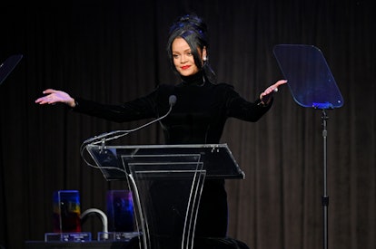 Rihanna stands at a podium with hands spread wide to the audience