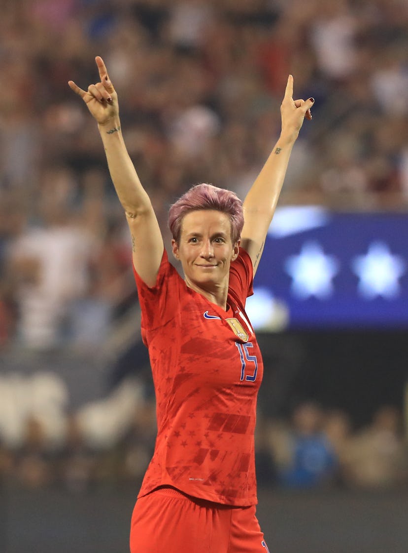 Megan Rapinoe celebrates with 2 hands in the air. Her quotes on equal pay are perfect for Internatio...