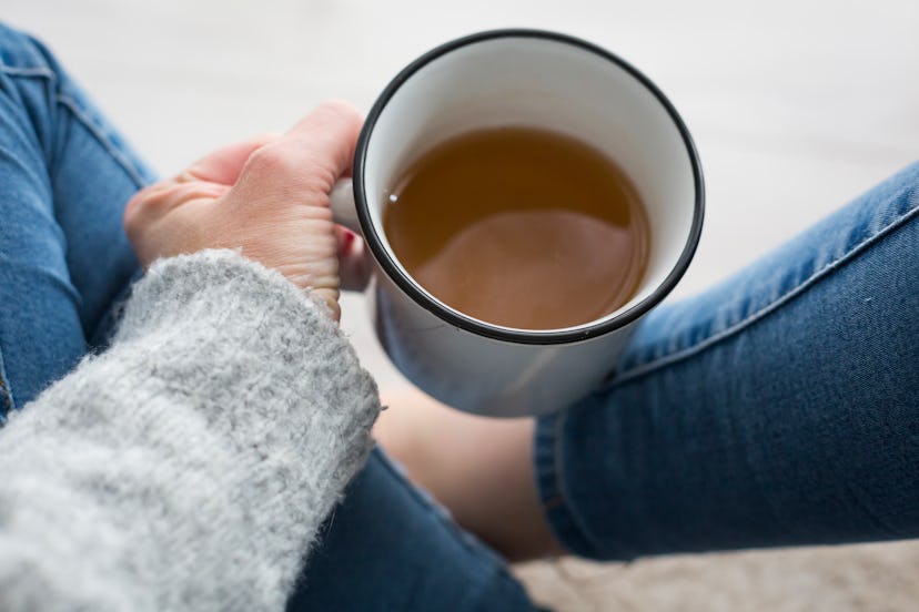 A woman sits crossed legged, holding a cup of coffee. Feeling depressed can be a sign your metabolis...