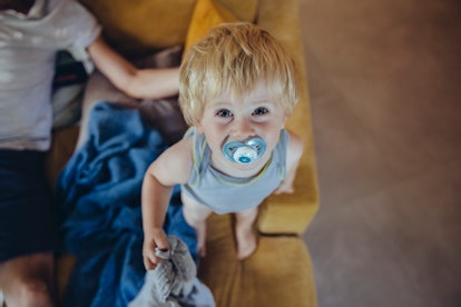 A small child looks up at the camera with a light blue pacifier in their mouth. Hiccups activate bra...