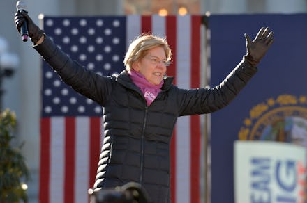 Elizabeth Warren in a black jacket with the American flag in the background