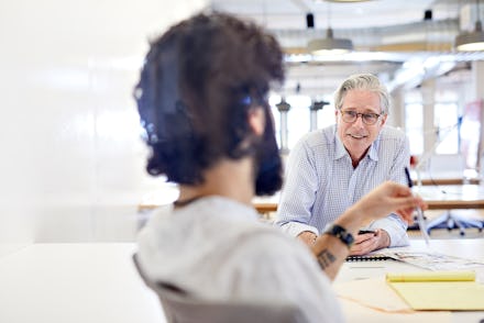Two colleagues, one younger and one older, talking at work